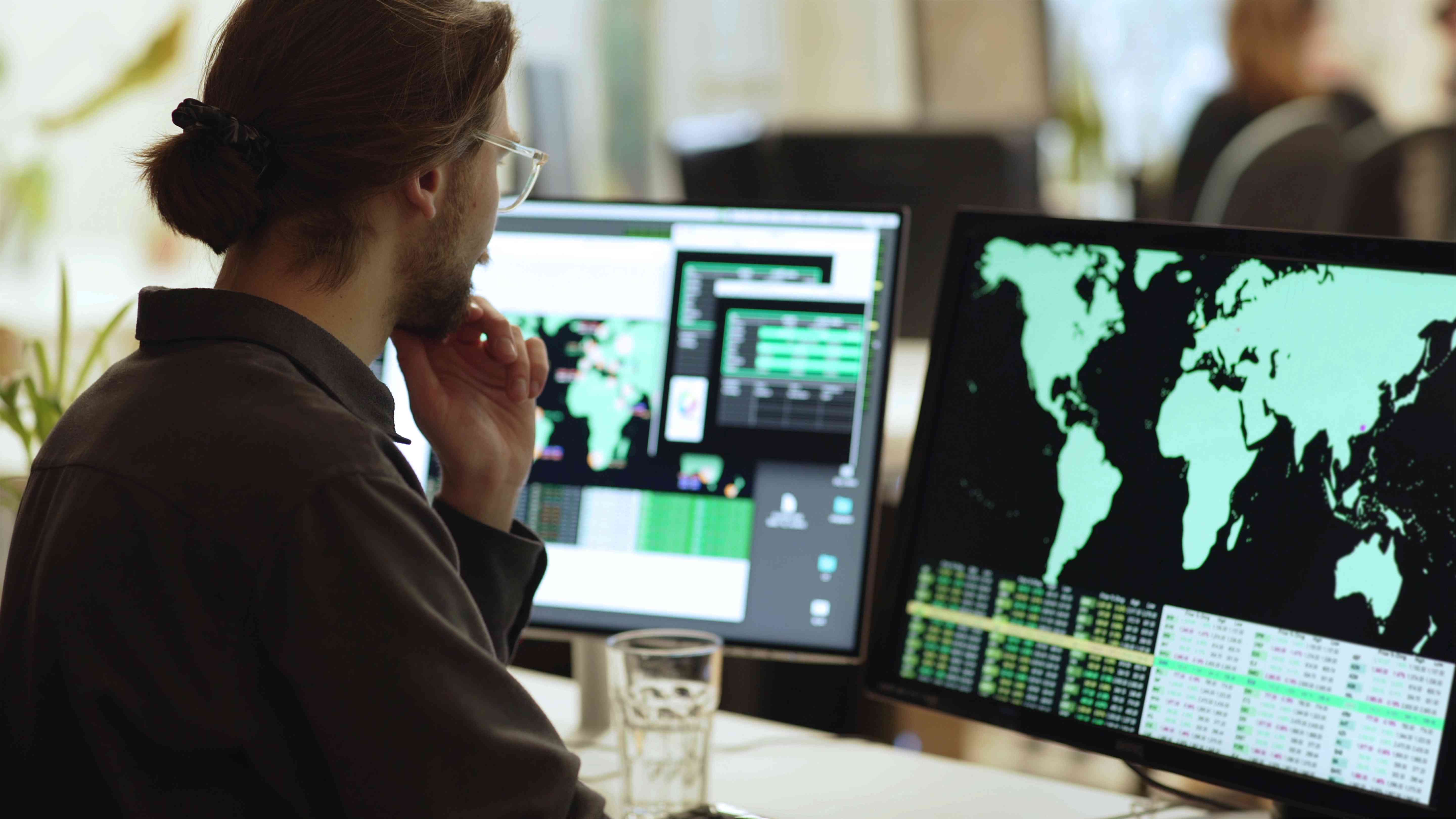 Young man sitting before a computer monitor showing a map of the world