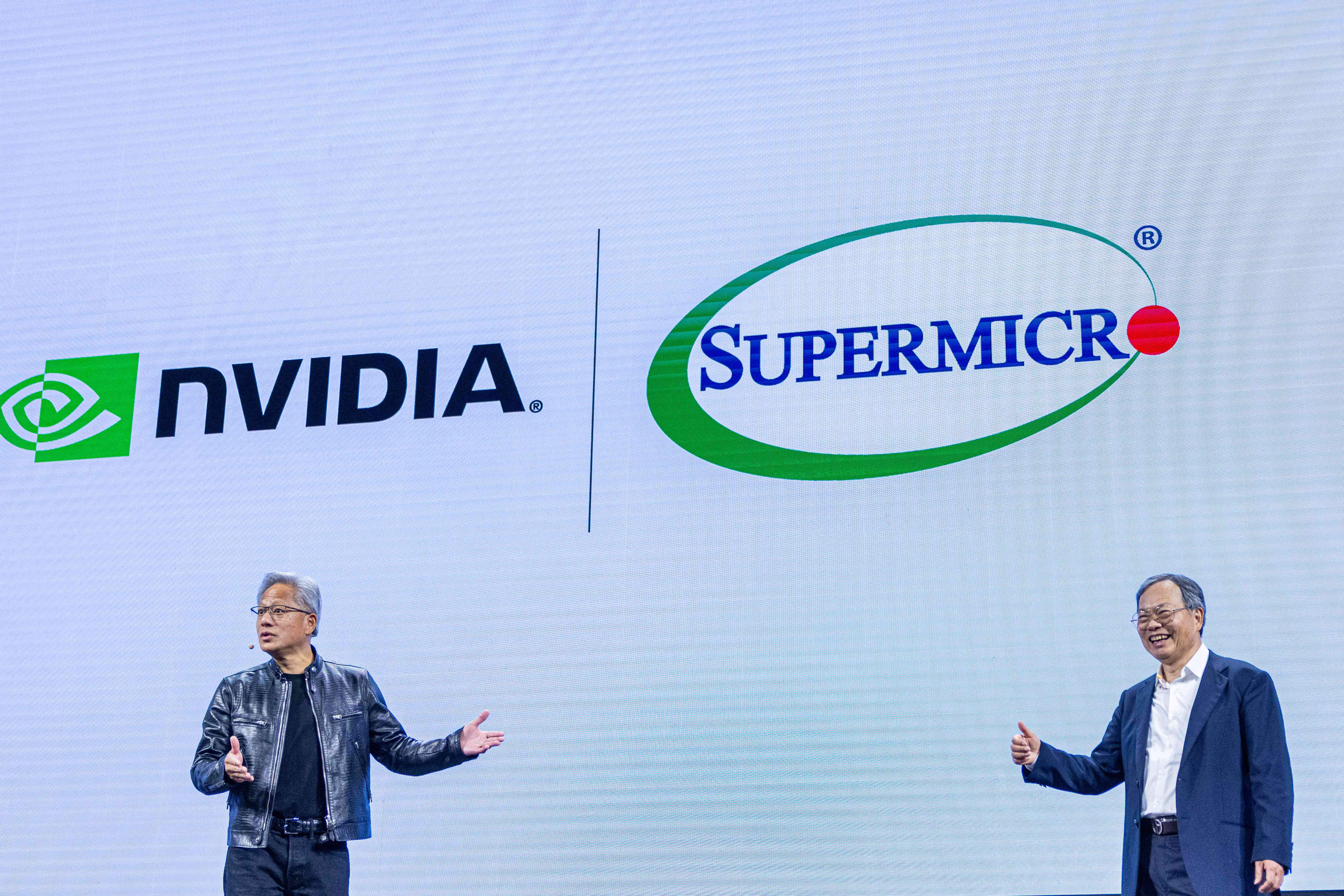 Nvidia CEO Jensen Huang and Super Micro CEO Charles Liang speak on stage beneath the logos of their companies.