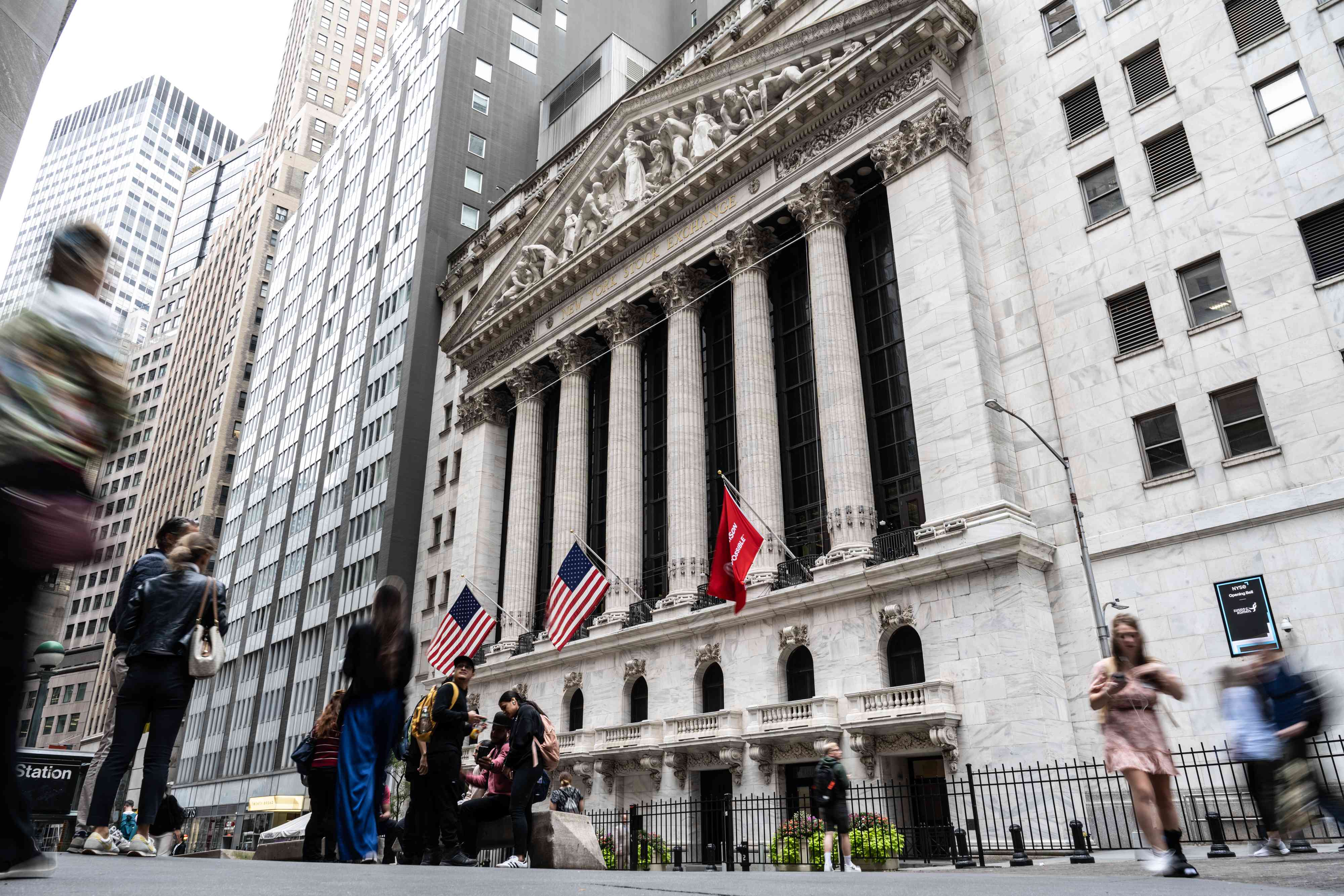 Several people walk past the New York Stock Exchange building in New York City. 