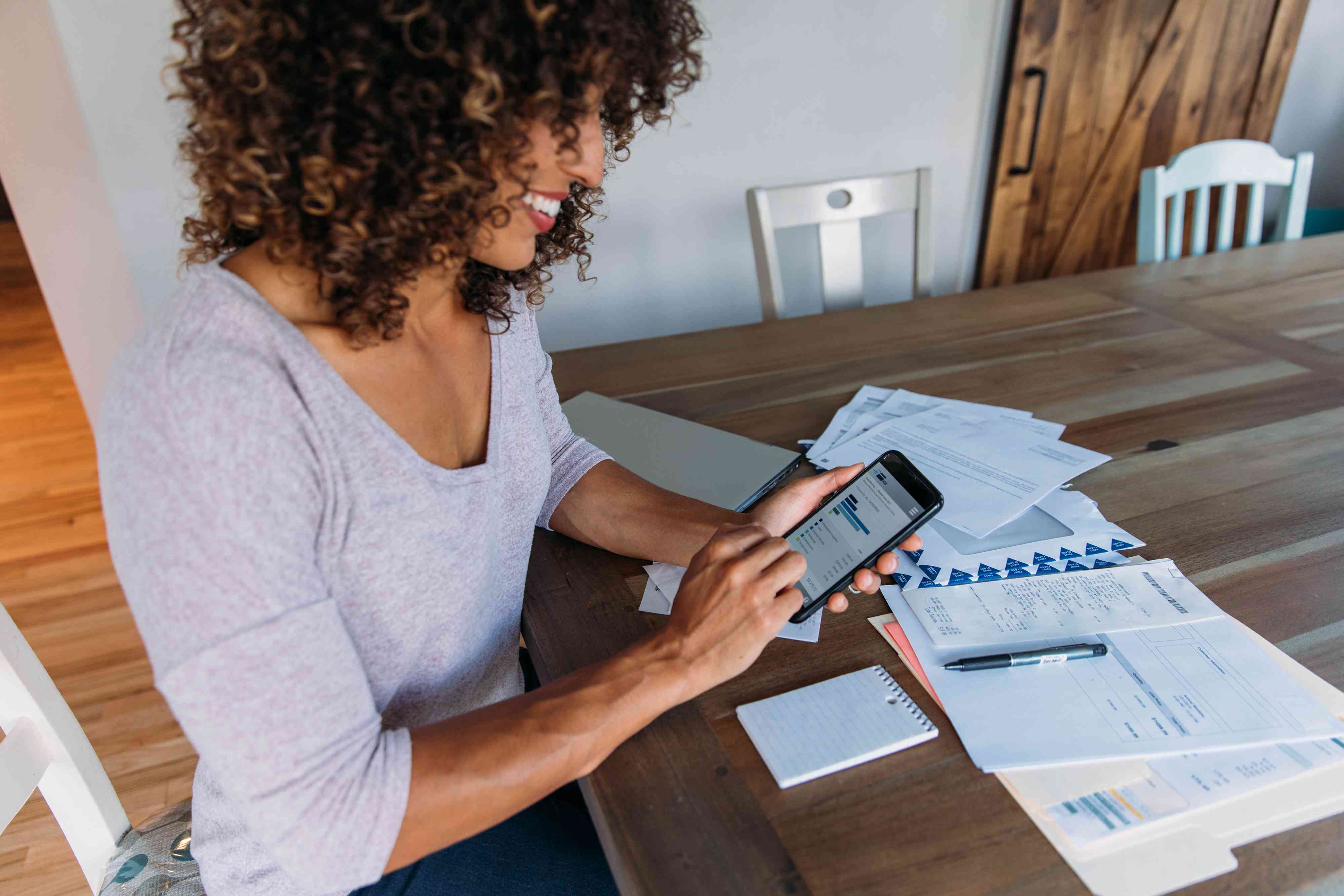 Woman working on her finances at home on her smartphone