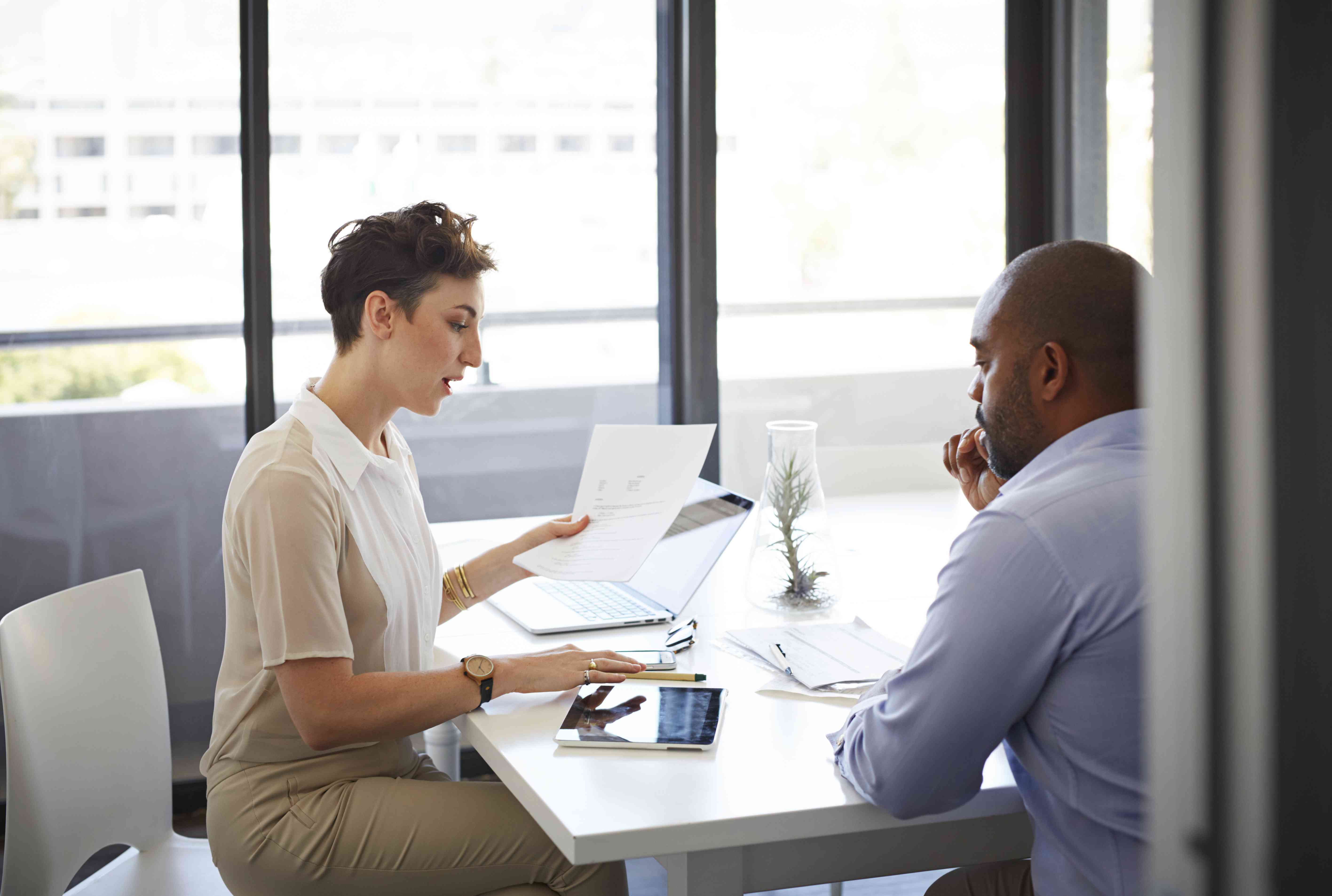 Business colleagues sit at a table in an office and discuss the timing of their upcoming new securities issue and complete SEC Form S-1.