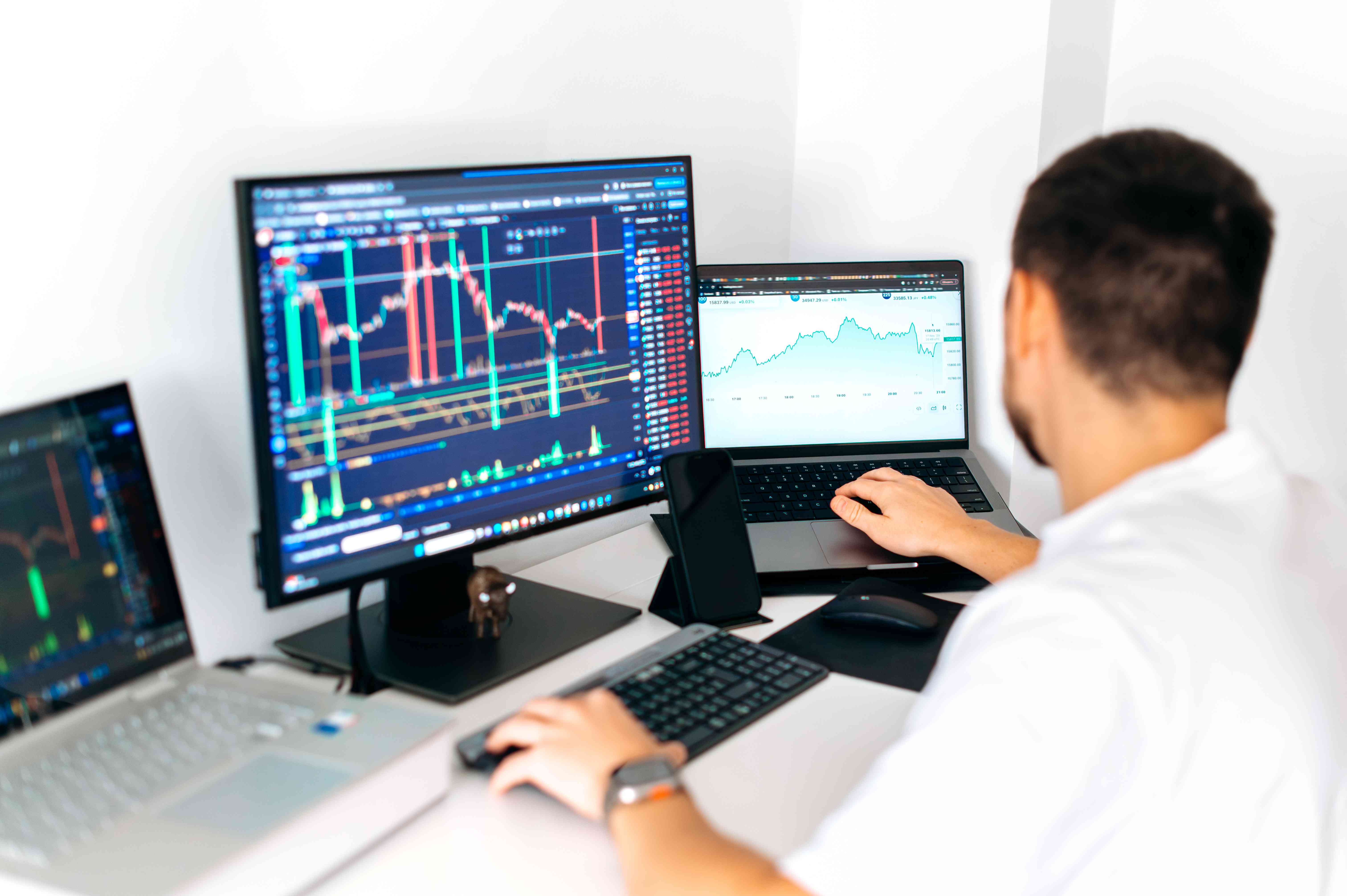 A day trader uses multiple computers and monitors as they watch the price and liquidity of a stock they follow.